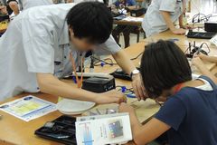 はんだ付けの補助をする学生の様子