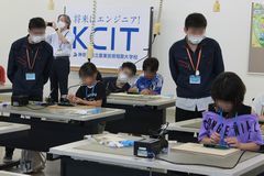 心配そうに作業をみる学生スタッフの様子